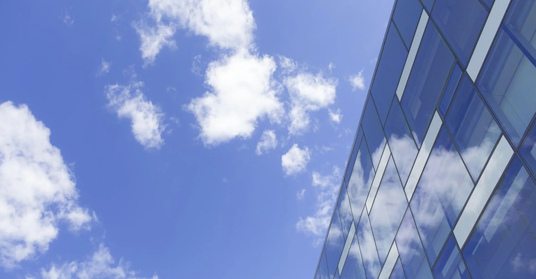 Façade vitrée reflétant un ciel bleu